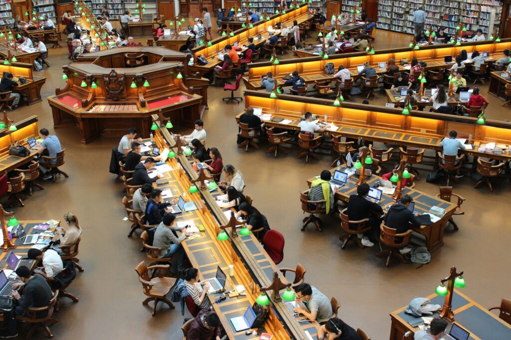library-la-trobe-study-students-159775-159775 A lively university library scene with students studying diligently at wooden desks.