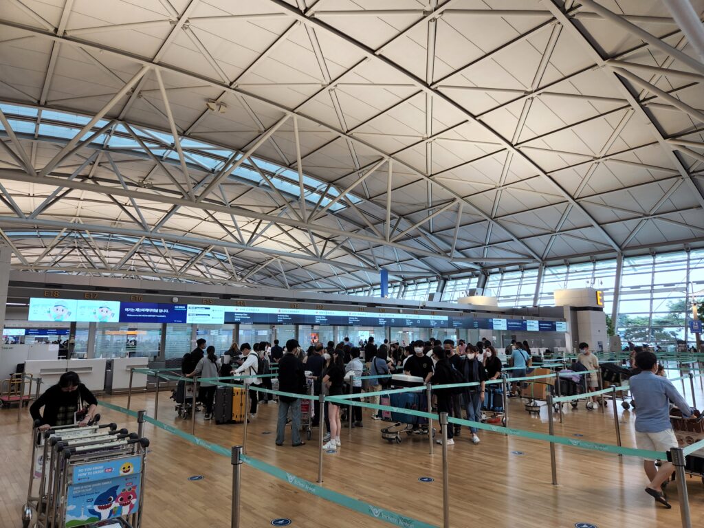 에어캐나다 체크인 데스크 앞에서 보딩을 준비하며 줄을 서고, 짐을 직접 부치는 캐나다 조기유학생들의 모습